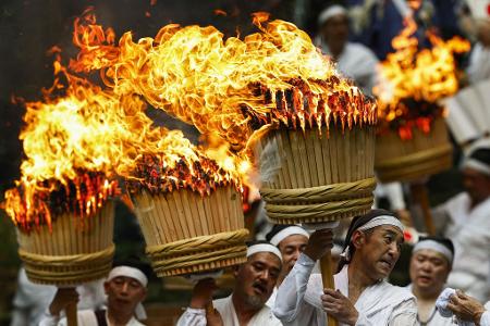 Teilnehmer tragen bei einem traditionellen Feuerfest in Japan riesige Fackeln. 
