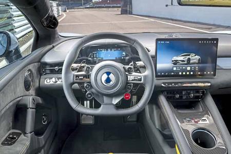 Cockpit und Innenraum eines modernen Sportwagens mit digitalem Display und Carbon-Elementen, fotografiert auf einer Rennstrecke.