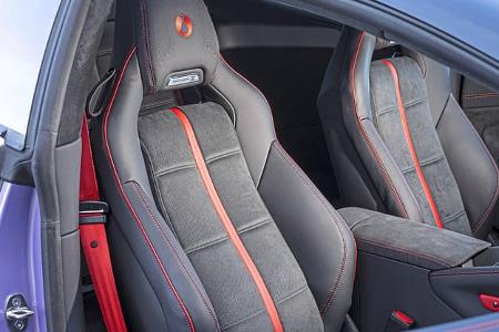 Detailaufnahme von Sportsitzen im Innenraum eines modernen Fahrzeugs, schwarze Leder-Alcantara-Kombination mit roten Akzenten.
