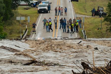 Menschen stehen zusammen und beobachten, wie der Perdenales River die Ranch Road 1623 in in Texas überflutet.
