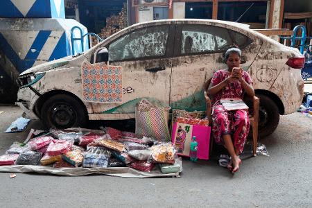 Indien - Verkäuferin mit Handy verkauft Taschen