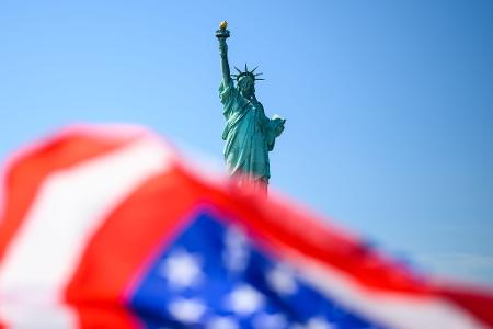 Die Fahne der USA weht vor der Freiheitsstatue.