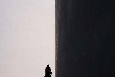 Eine Frau zeichnet sich als Silhouette vor der sonnenbeschienenen Fassade eines Gebäudes in in Kalifornien ab.