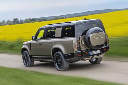 Land Rover Defender 130 D250 fährt auf einer Landstraße an einem blühenden Rapsfeld vorbei.