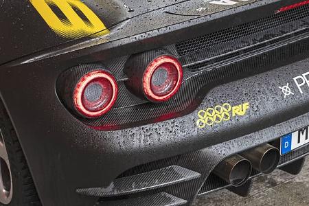 Detailaufnahme des Hecks eines Ruf 8Zylinder Prototyp-Sportwagens mit Carbon-Karosserie, markanten runden Rückleuchten und Doppelrohrauspuff. Sichtbar sind gelbe Ruf-Logos, der Schriftzug 'PROTOTYP' und ein deutsches Kennzeichen. Die Karosserie ist nass und zeigt Wassertropfen.