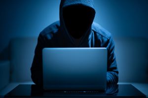 Hacker mit Kapuze vor Laptop