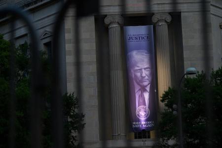 Ein Porträt von US-Präsident Donald Trump ist durch einen Sicherheitszaun am Justizministerium in Washington zu sehen, während in der Nähe das Dinner der White House Correspondents’ Association stattfindet.