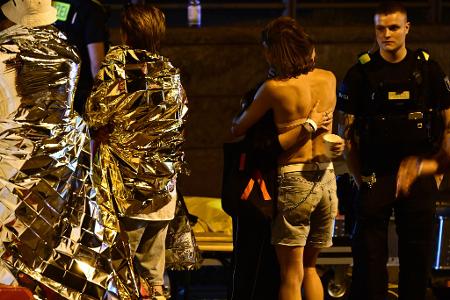 Menschen hüllen sich in Rettungsdecken und umarmen sich.