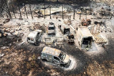 Aus der Luft sind ausgebrannte Autos nach einem Waldbrand zu sehen.