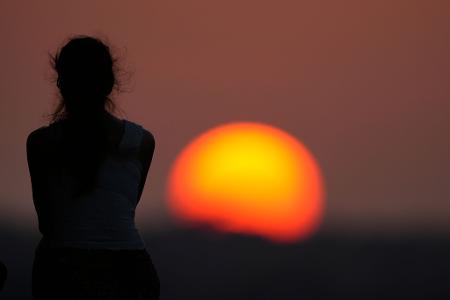 Eine Frau beobachtet den Sonnenuntergang.