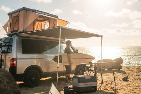 Surf, Sonne, Salz: Prime Tech Utah Dachzelt am Strand, Markise ausgefahren, das Meer im Rücken. Perfektes Setup für alle, die Wellen lieben und unter freiem Himmel träumen.