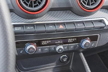 Detailaufnahme der Mittelkonsole und Klimabedieneinheit eines Audi SQ2 TSFI quattro S-tronic. Sichtbar sind Lüftungsdüsen mit roten Akzenten, Bedientasten und das digitale Klimadisplay.