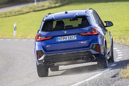 BMW X1 M35i xDrive in blauer Lackierung auf einer Landstraße, Heckansicht in Kurvenfahrt.