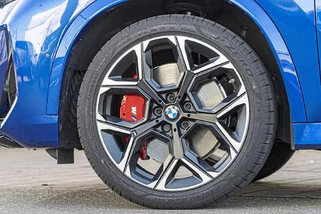 Detailaufnahme des Vorderrads und der Bremsanlage eines BMW X1 M35i xDrive, blau lackiert.