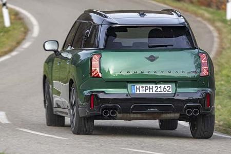 Grüner Mini JCW Countryman 4all fährt auf einer kurvigen Landstraße, fotografiert von hinten.