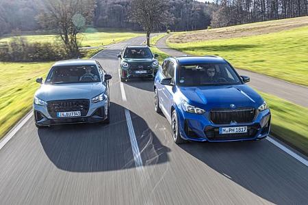 Drei Kompakt-SUVs (Audi SQ2, BMW X1 M35i, Mini JCW Countryman) fahren nebeneinander auf einer Landstraße.