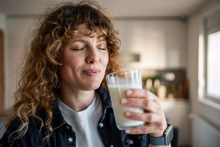 Frau steht in der Küche und trinkt ein Glas Milch