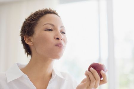 Frau kaut einen Apfel