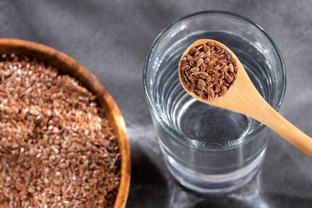 Schüssel mit Leinsamen und Glas Wasser