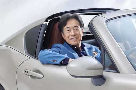 Ein Mann sitzt in einem hellen Mazda Cabrio, lehnt sich entspannt aus dem geöffneten Fenster und blickt freundlich in die Kamera.