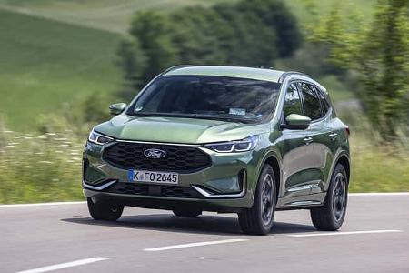 Ford Kuga 1,5l EcoBoost SUV in Grün auf Landstraße, Frontansicht, fahrend, Sommerlandschaft im Hintergrund.