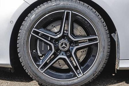 Detailaufnahme eines Mercedes Benz A200 AMG-Leichtmetallrads mit Bridgestone-Reifen und gelochter Bremsscheibe.