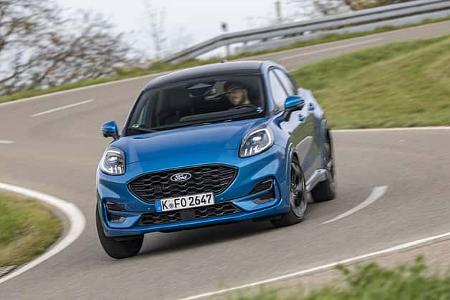Ein blauer Ford Puma 1.0 EcoBoost fährt dynamisch auf einer kurvigen Landstraße.