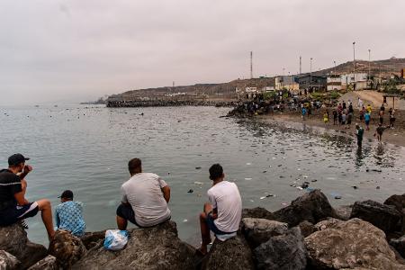 Migranten blickten von Felsen aus, während andere aus der spanischen Enklave Ceuta nach Marokko zurückkehrten.