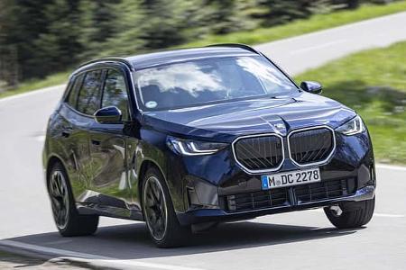 BMW X3 20 xDrive fährt auf einer Landstraße durch eine Kurve. Das SUV ist in dunkler Lackierung zu sehen.