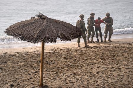 Soldaten der spanischen Armee leisten einem Migranten Hilfe, der von Marokko aus zur spanischen Exklave Ceuta geschwommen ist.