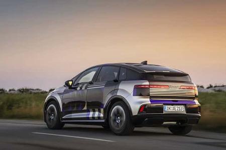 Audi A2 e-tron Erlkönig auf Landstraße bei Sonnenuntergang, getarnter Prototyp von hinten fotografiert.
