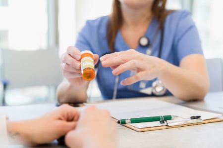 Ärztin erklärt Patient den Inhalt eines Tablettenröhrchens