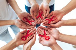 Menschen stehen im Kreis und halten HIV-Schleifen in ihren Händen