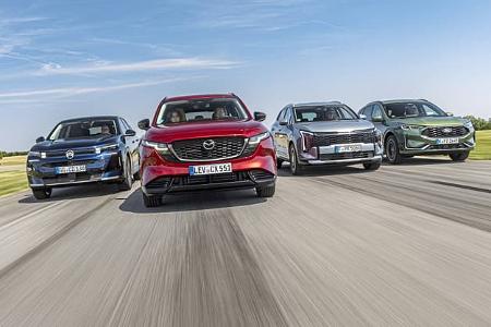 Vier aktuelle SUV-Modelle (Citroën C5 Aircross Hybrid, Mazda CX-5, Kia Sportage, Ford Kuga) fahren nebeneinander auf einer Landstraße. Die Fahrzeuge sind frontal und dynamisch im Verband aufgenommen, alle Modelle sind klar erkennbar.