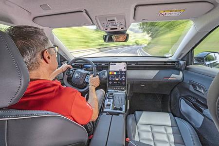 Innenraumaufnahme eines Citroen C5 Aircross Hybrid während der Fahrt, Blick über die Schulter des Fahrers auf das Cockpit und die Mittelkonsole.