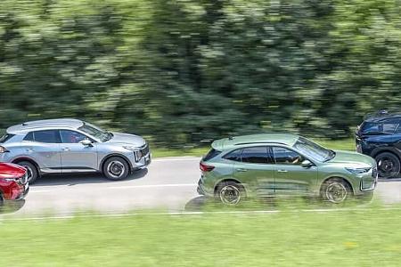 Vier aktuelle SUV-Modelle (Mazda CX-5, Citroen C5 Aircross Hybrid, Ford Kuga, Kia Sportage) fahren nebeneinander auf einer Landstraße.