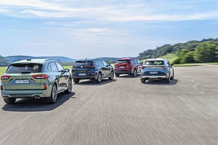 Vier Mittelklasse-SUVs, namentlich Mazda CX-5, Citroën C5 Aircross Hybrid, Ford Kuga und Kia Sportage, fahren nebeneinander auf einer Landstraße in ländlicher Umgebung. Die Fahrzeuge sind aus der Heckperspektive zu sehen.