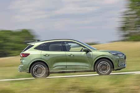 Ford Kuga 1,5l EcoBoost SUV in Seitenansicht, fahrend auf Landstraße, grüne Lackierung, Sommerlandschaft.