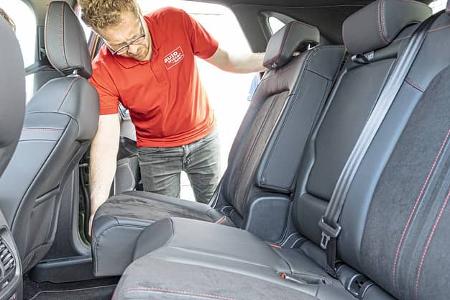 Innenraumaufnahme eines Ford Kuga 1,5l EcoBoost, ein Mann klappt die Rücksitzbank um.