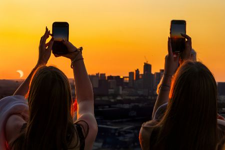 Zwei Frauen mit Handys filmen den Sonnenuntergang