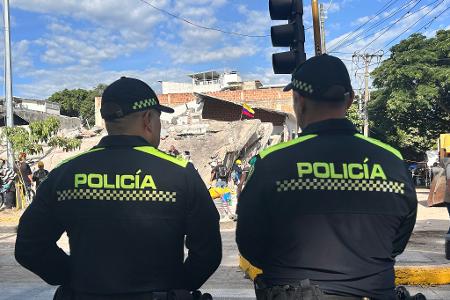 Polizisten stehen vor einem abgestürzten Gebäude.