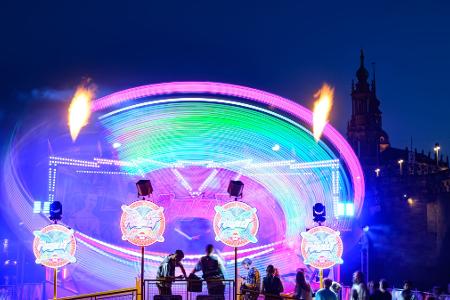 Ein dynamisches Rundfahrgeschäft dreht sich beim Dresdner Stadtfest Canaletto vor der historischen Altstadtkulisse.