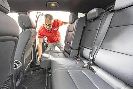 Innenraumaufnahme eines Mercedes GLB 250+ mit Fokus auf die Rücksitzbank. Ein Mann im roten Hemd beugt sich von außen in das Fahrzeug.