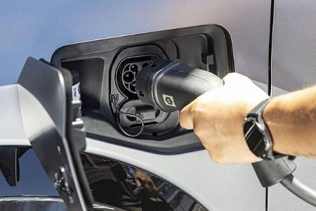 Detailaufnahme des Ladevorgangs eines Alpine A290GTS Elektrofahrzeugs. Eine Hand hält den Ladestecker am Ladeanschluss des Autos.