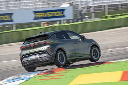 Der Cupra Raval fährt auf dem Hockenheimring über eine farbige Curbszone. Das Fahrzeug ist in sportlicher Seitenansicht zu sehen, die Hinterräder heben leicht ab.