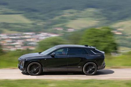 Seitenansicht eines schwarzen Cadillac Lyriq-V auf einer Landstraße mit unscharfem Hintergrund.