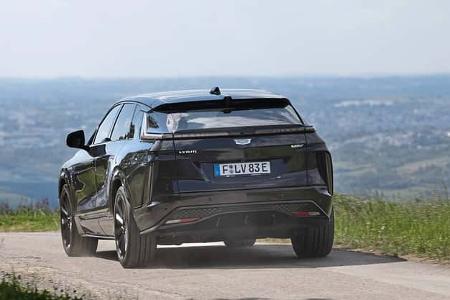 Cadillac Lyriq-V auf Landstraße, Heckansicht, im Fahrbetrieb, ländliche Umgebung, Sommer.