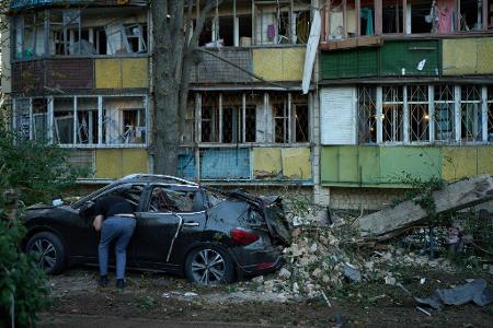 Ein Anwohner blickt nach einem nächtlichen russischen Angriff in ein zerstörtes Auto.