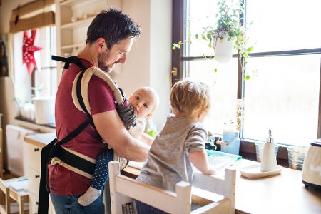 Vater mit einem zwei kleinen Kindern beim Abwasch