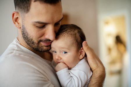 Mann hält sein Baby an sich gedrückt